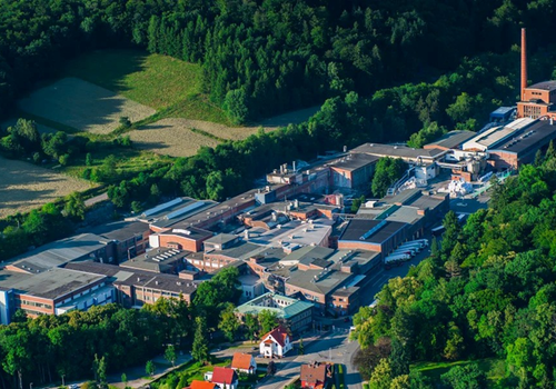 Luftaufnahme einer großen Industrieanlage umgeben von dichtem Wald in Herzberg.